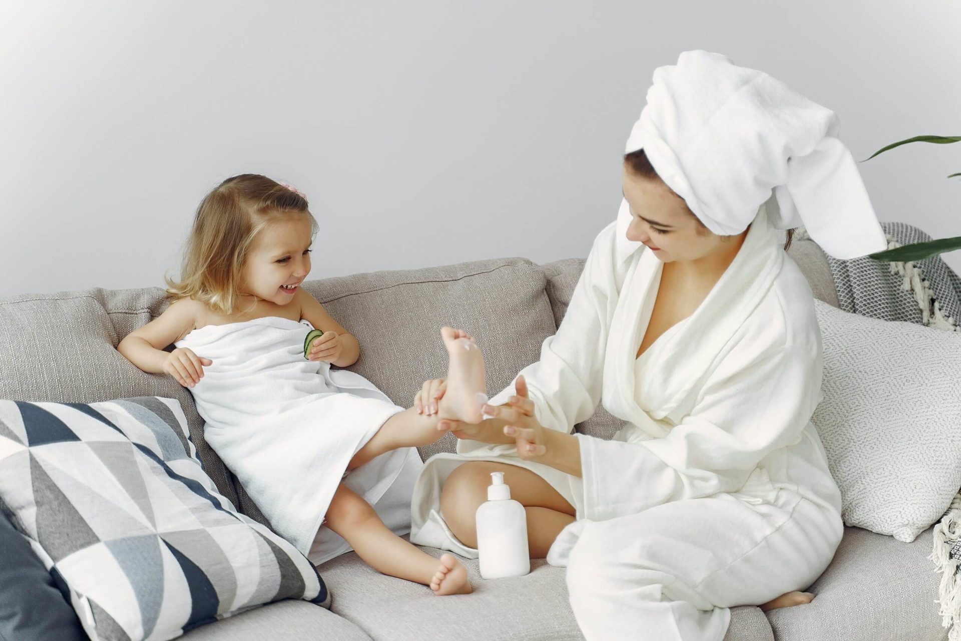 mom rubbing lotion on little girls feed